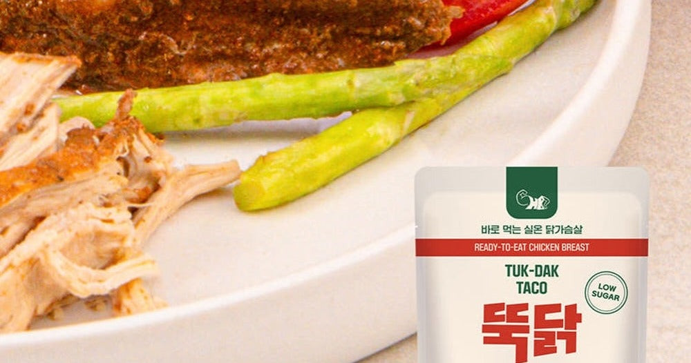 Lean chicken breast with asparagus and tomato beside a Tuk-Dak Taco pack