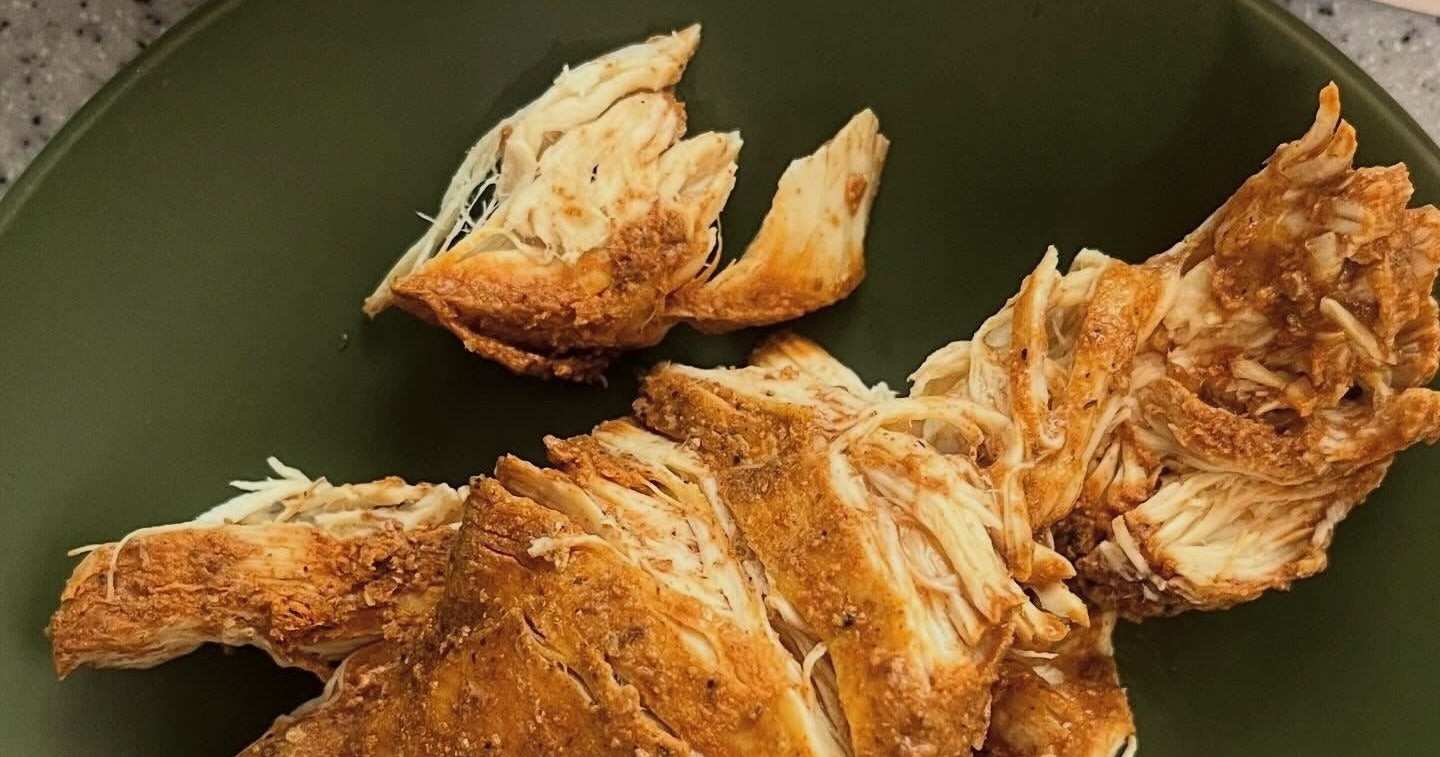 Shelf-stable seasoned chicken breast pulled apart on a green plate