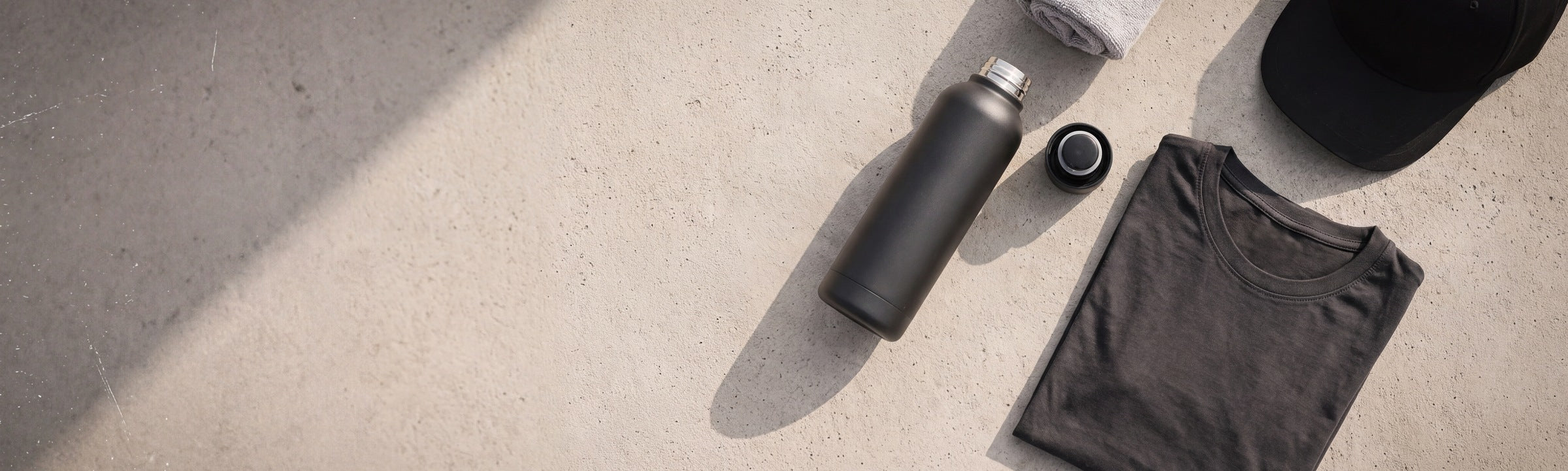 Training kit laid out on concrete: bottle, folded tee, cap and towel